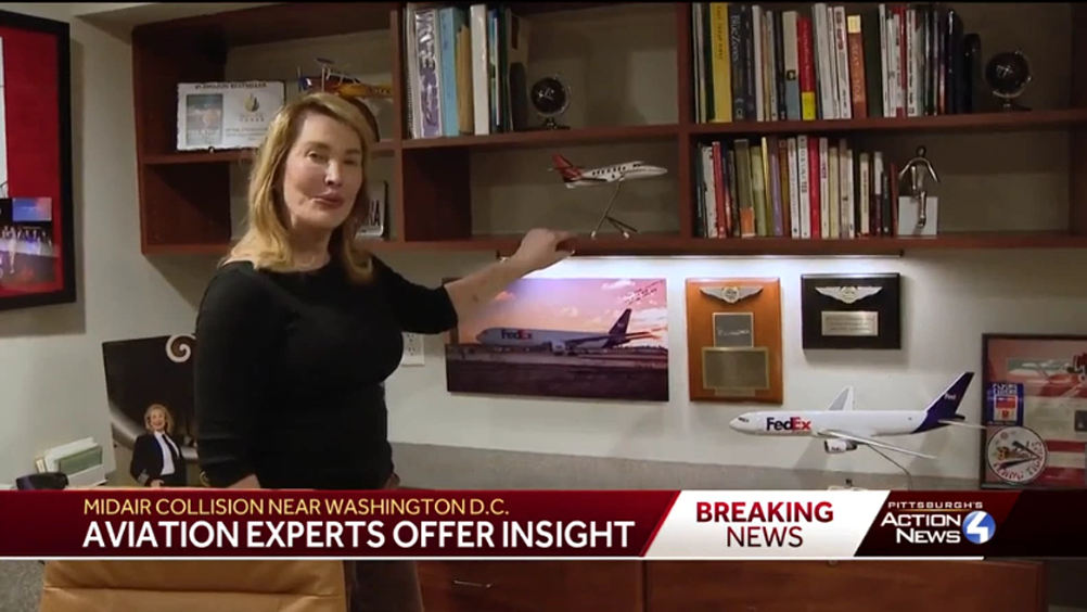 A woman in an office points to airplane models on a shelf. A news caption reads, "Midair collision near Washington D.C. Aviation experts offer insight.